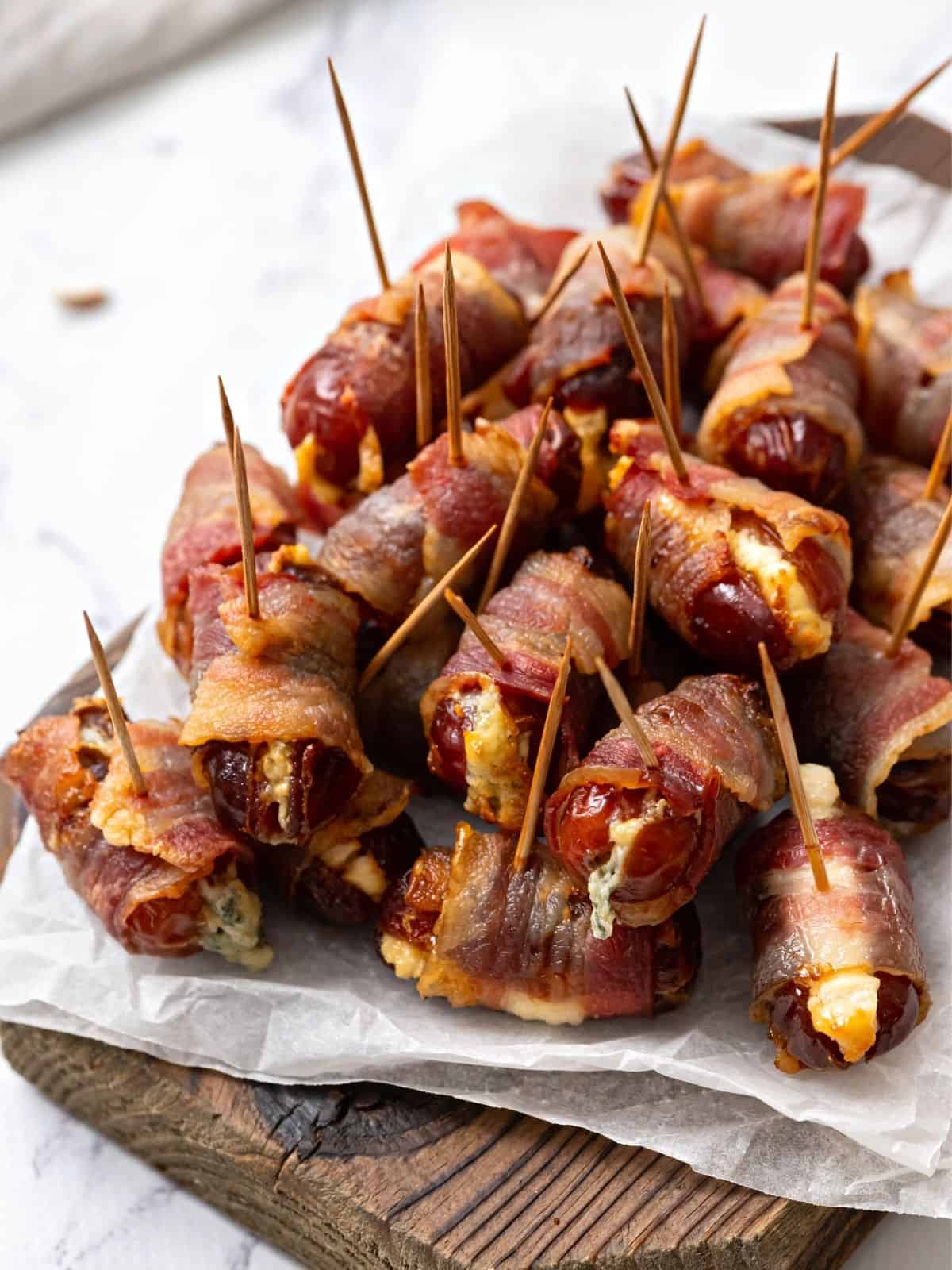 Dates stuffed with goat cheese and wrapped in bacon on platter. 