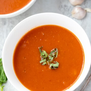 Bowl of tomato soup with basil ribbons.