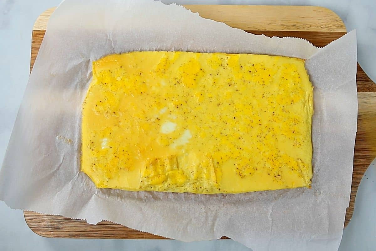 Baked Scrambled Eggs on parchment paper on cutting board.