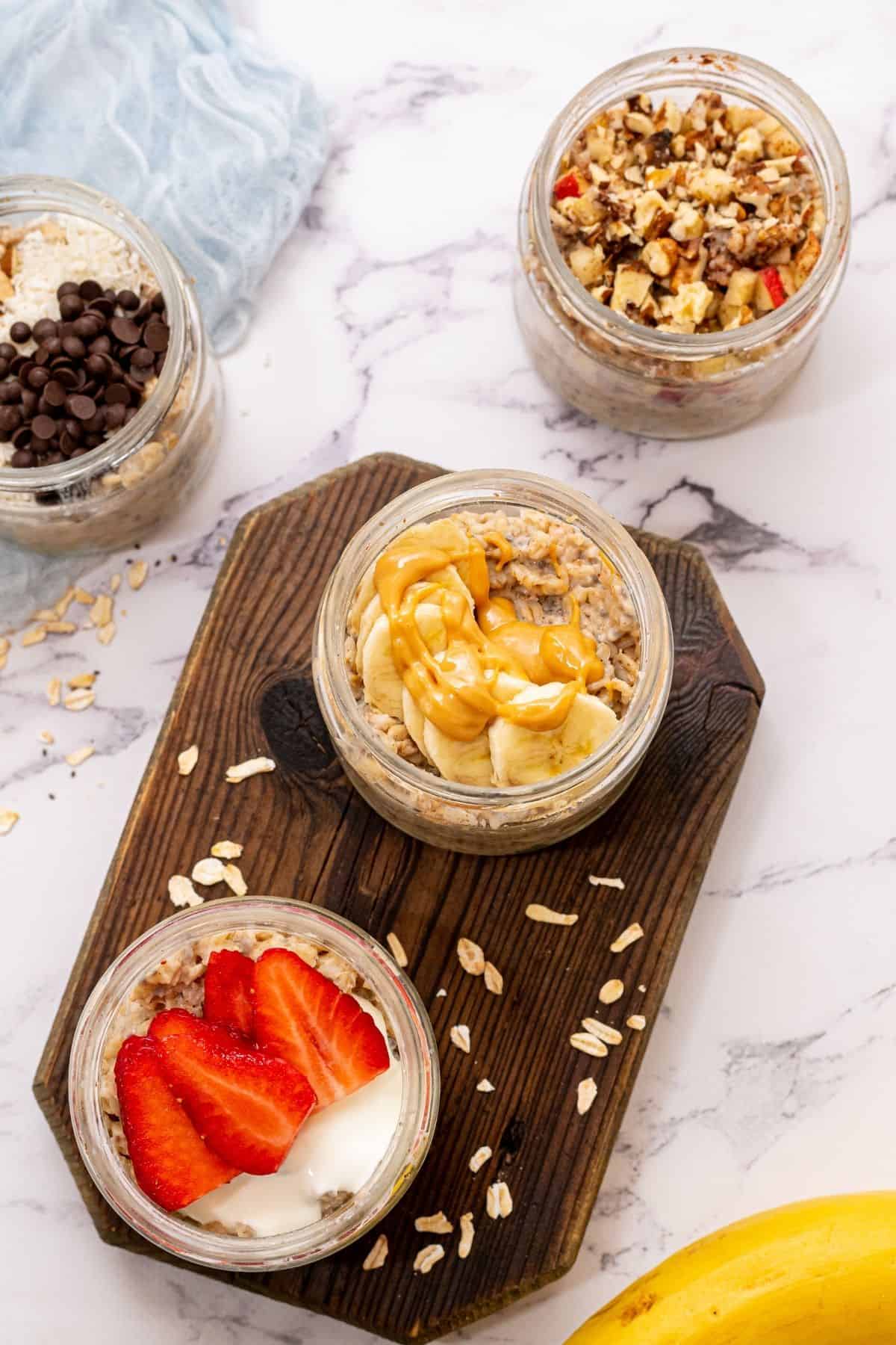Jars of overnight oatmeal topped with fresh fruit and almond butter. 