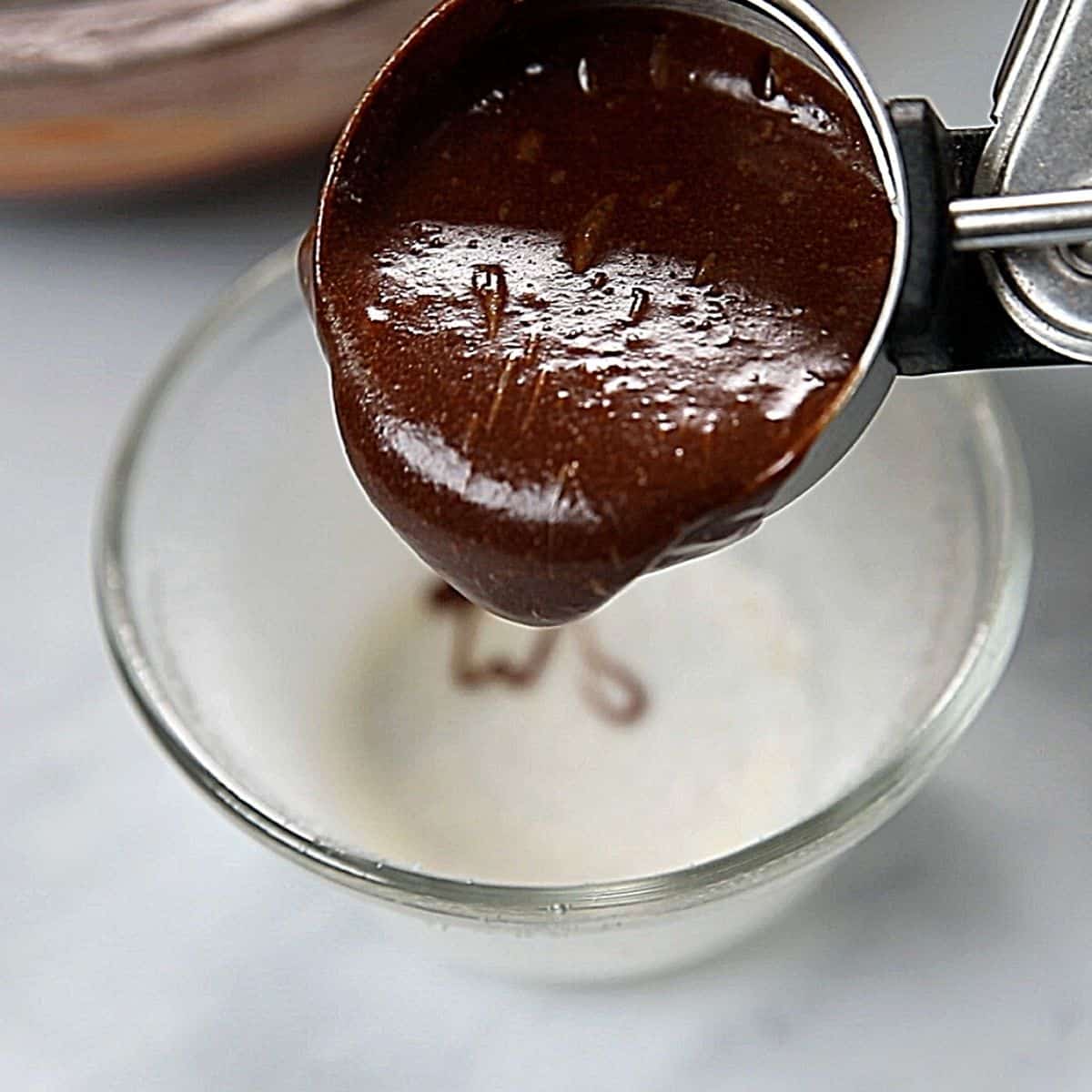 An ice scream scooping chocolate batter into ramekins.