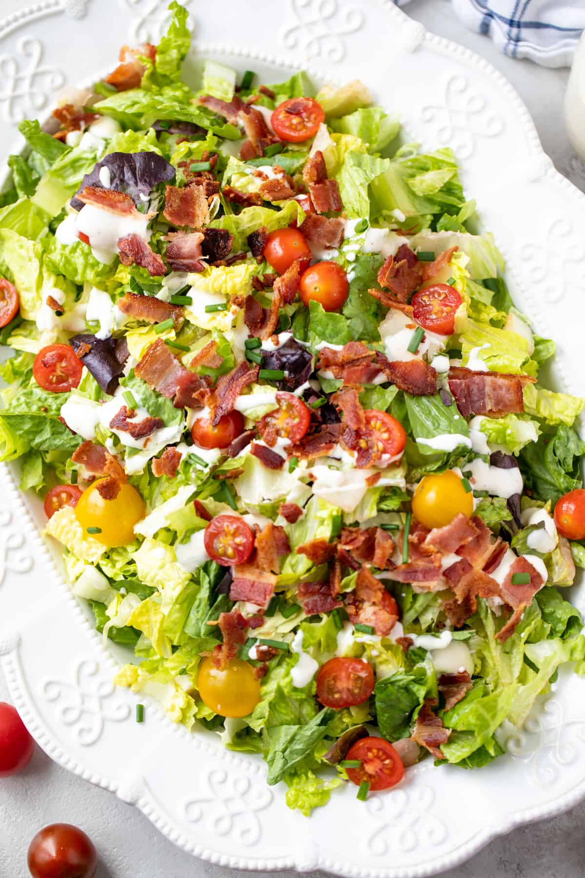 White platter with BLT Salad next to grape tomatoes.