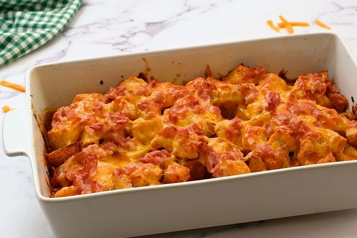Potatoes, chicken, and cheese baked in white casserole dish. 