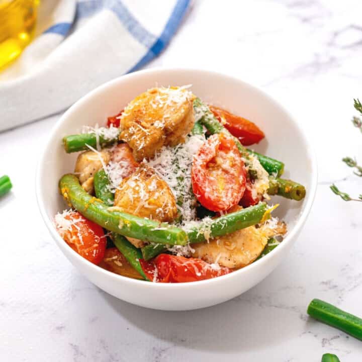 Bowl of chicken and green beans with tomatoes.