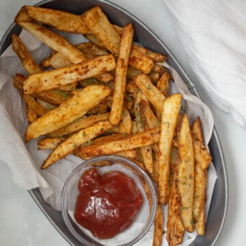 Basket of air fryer french fries served with ketchup.