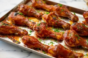 BBQ Chicken Legs on sheet pan brushed with BBQ Sauce.