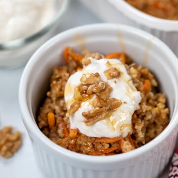Bowl of Carrot Cake Oatmeal topped with nuts maple syrup and yogurt.