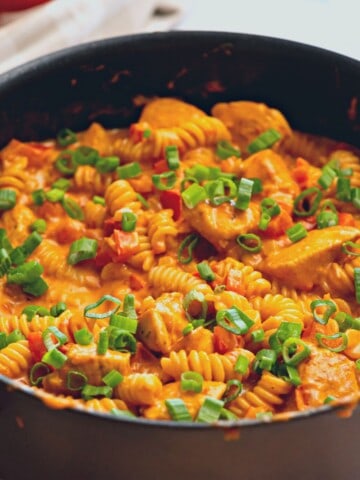 Skillet with Creamy Chicken Cajun Pasta topped with green onions.