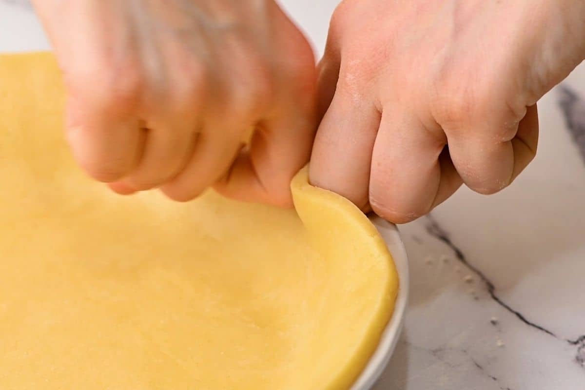 Using fingers to flute edges of pie crust. 