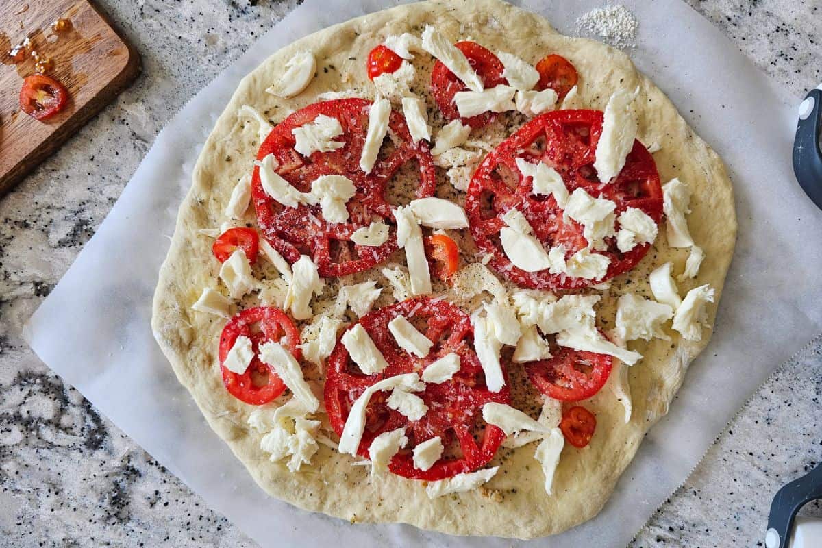 Pizza dough topped with mozzarella and fresh tomatoes.