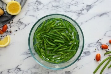 Steamed green beans in bowl of ice water.
