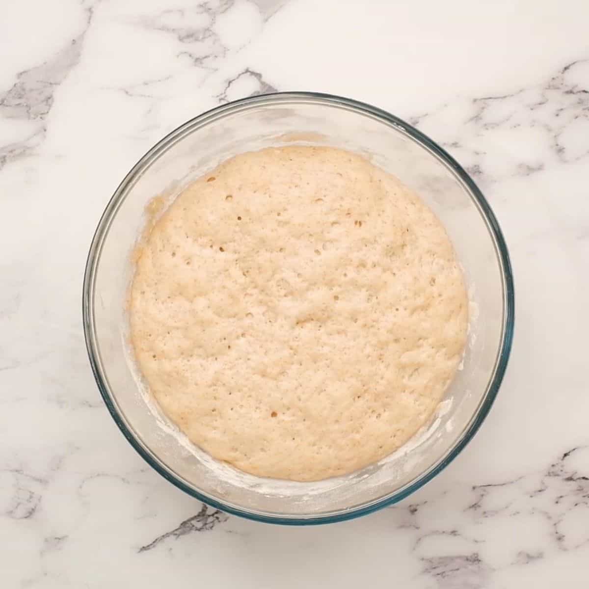 Bread dough in glass mixing bowl.