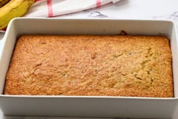 Baked Banana Cake in 9x13 white cake pan with golden brown coloring.