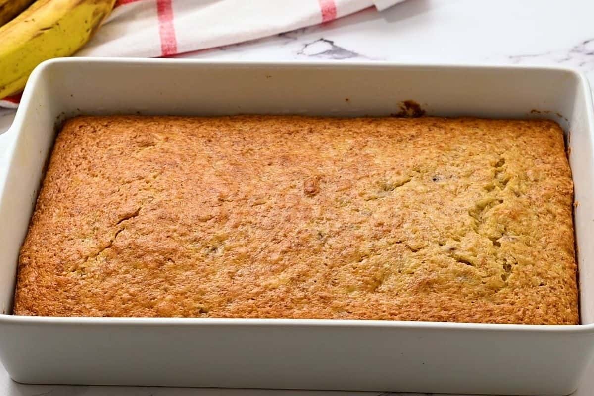 Baked Banana Cake in 9x13 white cake pan with golden brown coloring.