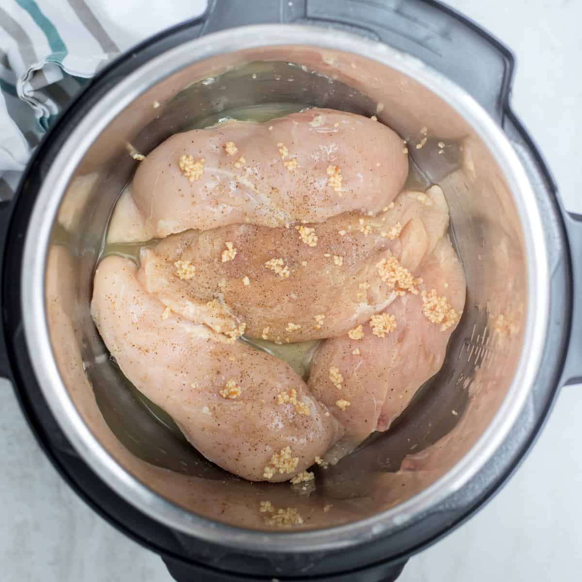 Instant Pot with 4 Chicken Breasts topped with pepper and garlic. 