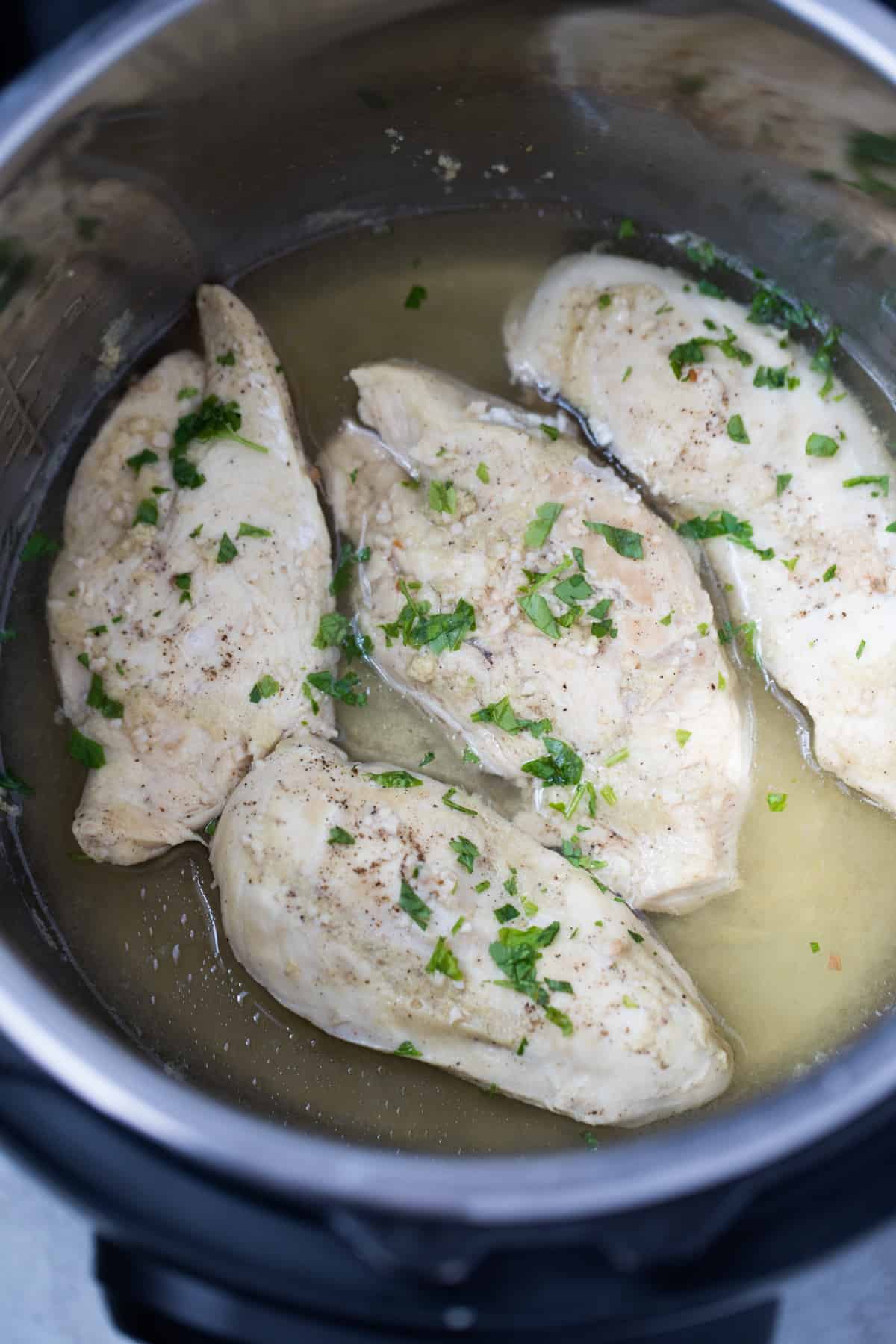 Four Chicken Breasts inside instant Pot sprinkled with parsley.