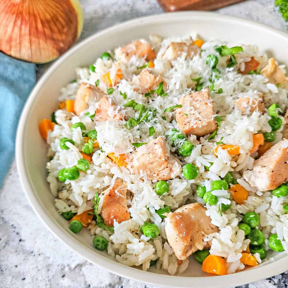 Bowl of instant pot chicken and rice with carrots and peas.