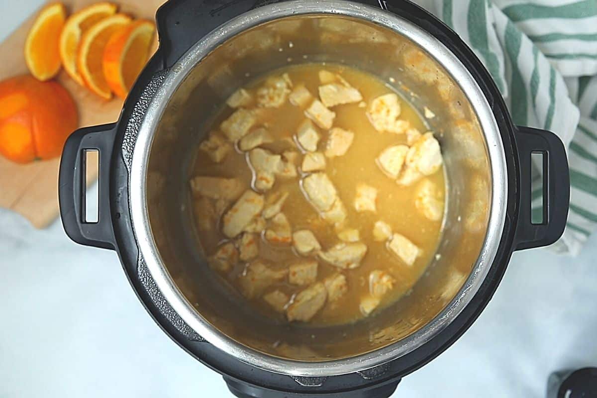Chicken inside inner pot with orange sauce. 