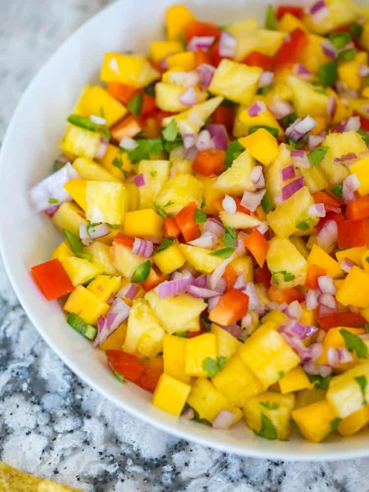 White serving bowl filled with pineapple mango salsa.