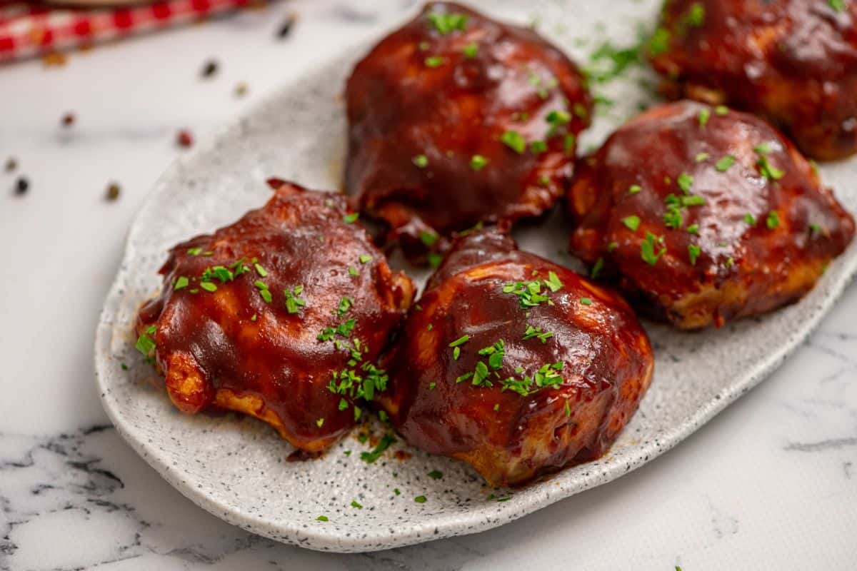 Close up of BBQ Chicken Thighs on white platter.