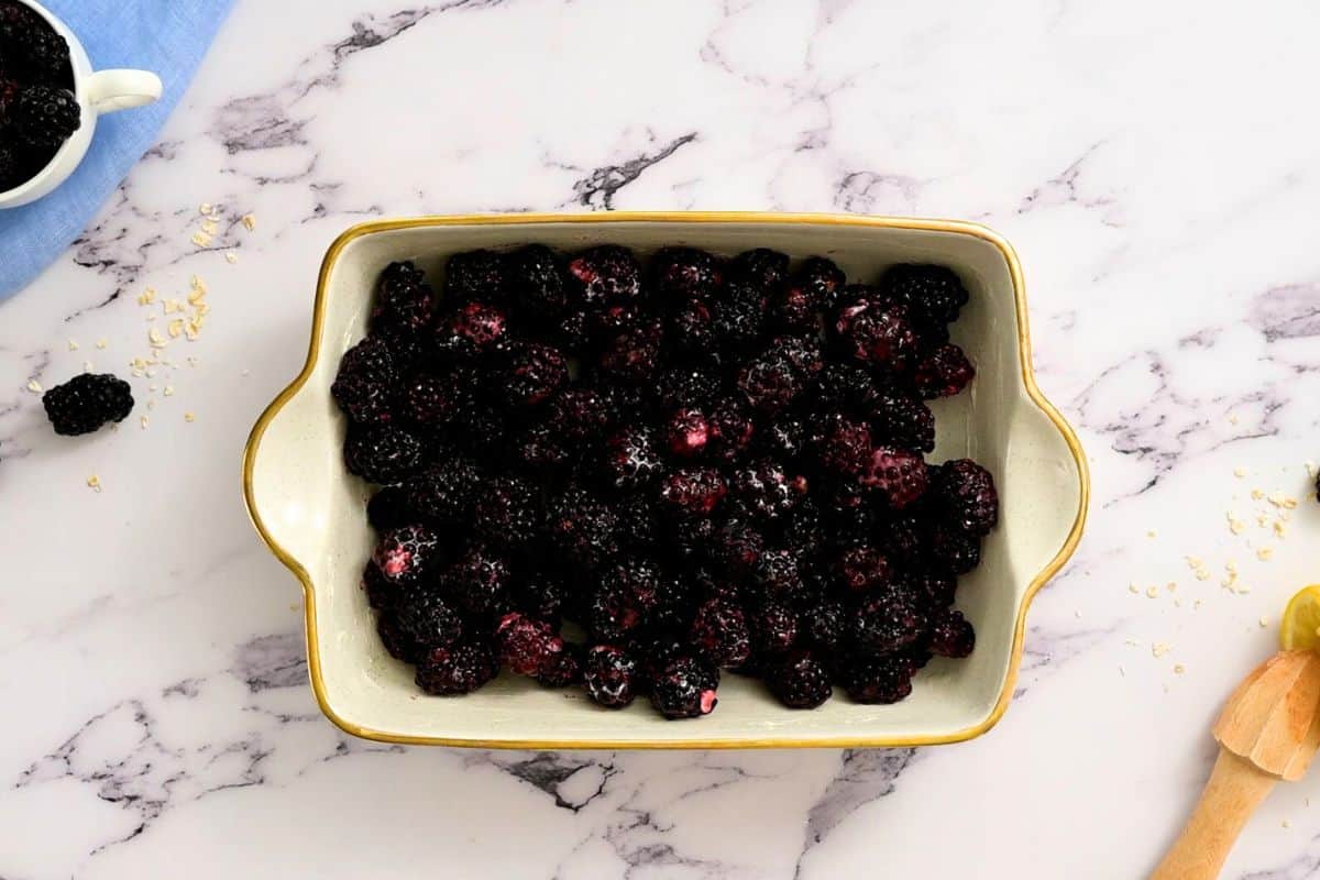 Blackberries tossed with sugar and cornstarch in buttered baking dish.