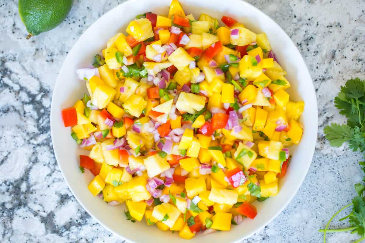 Pineapple Mango Salsa dished out in white serving bowl.
