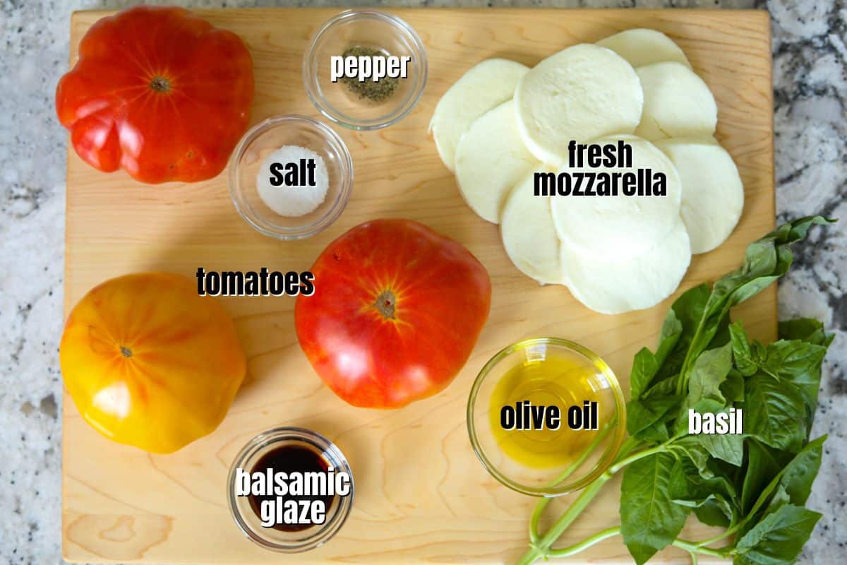 Ingredients for Caprese Salad labled on wooden cutting board.