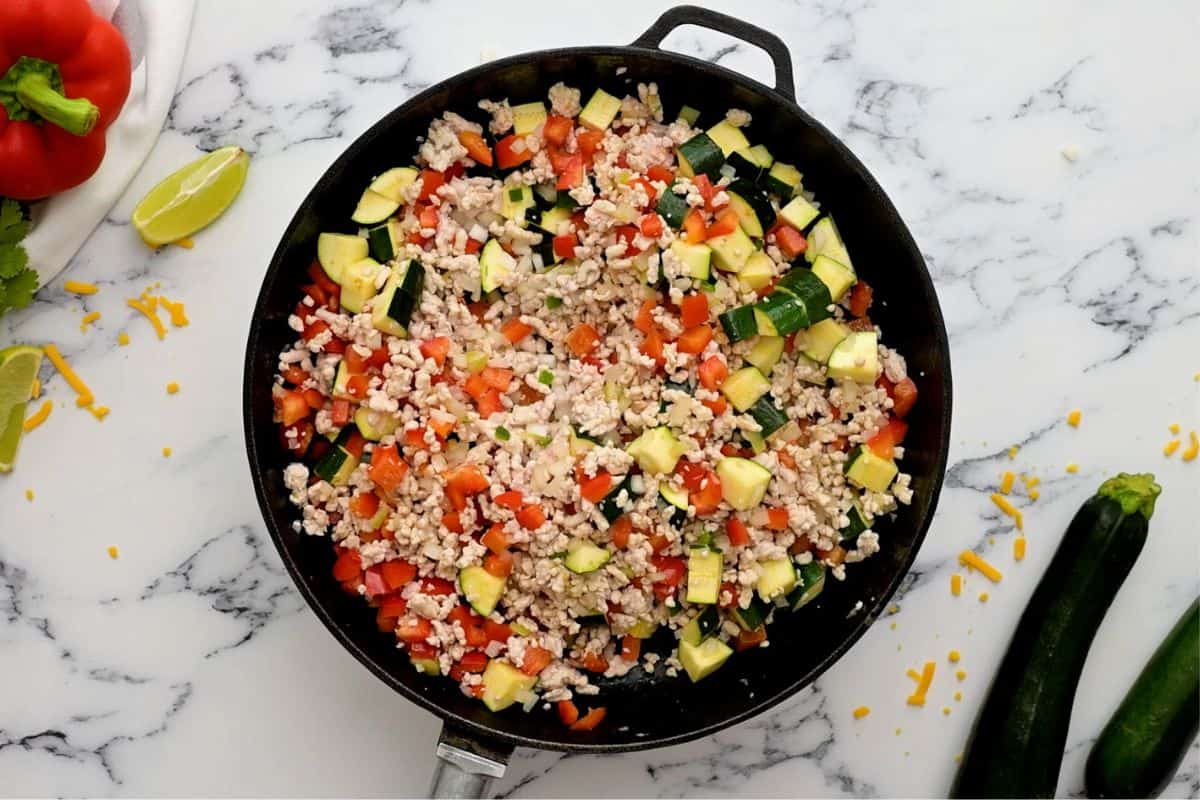 Ground turkey with peppers, zucchini, and jalapeno in skillet.