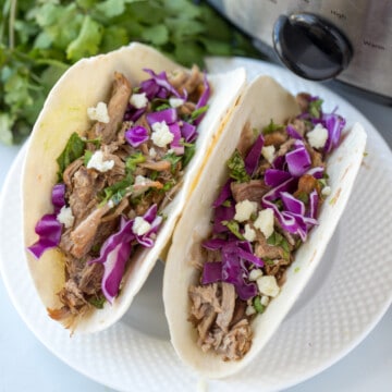 2 Pork tacos on white plate made with Slow Cooker Carnitas.