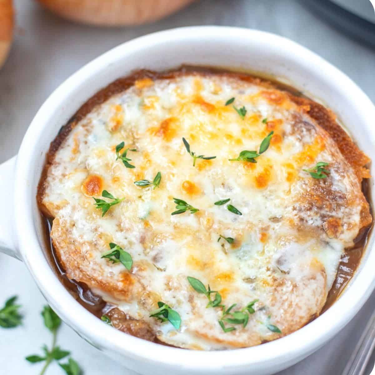 Bowl of french onion soup topped with fresh thyme. 