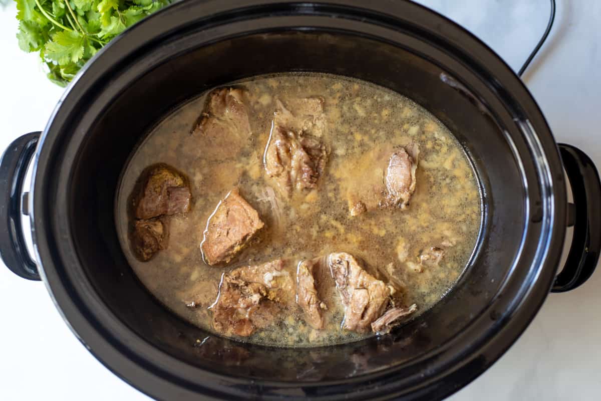 Cooked pork butt in Mexican Liquid in slow cooker. 