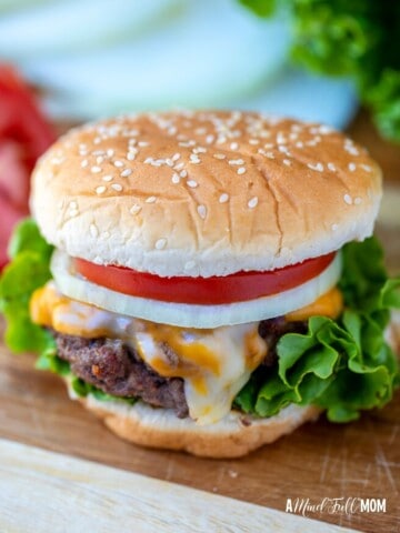 Hamburger on cutting board with lettuce and tomatoes.