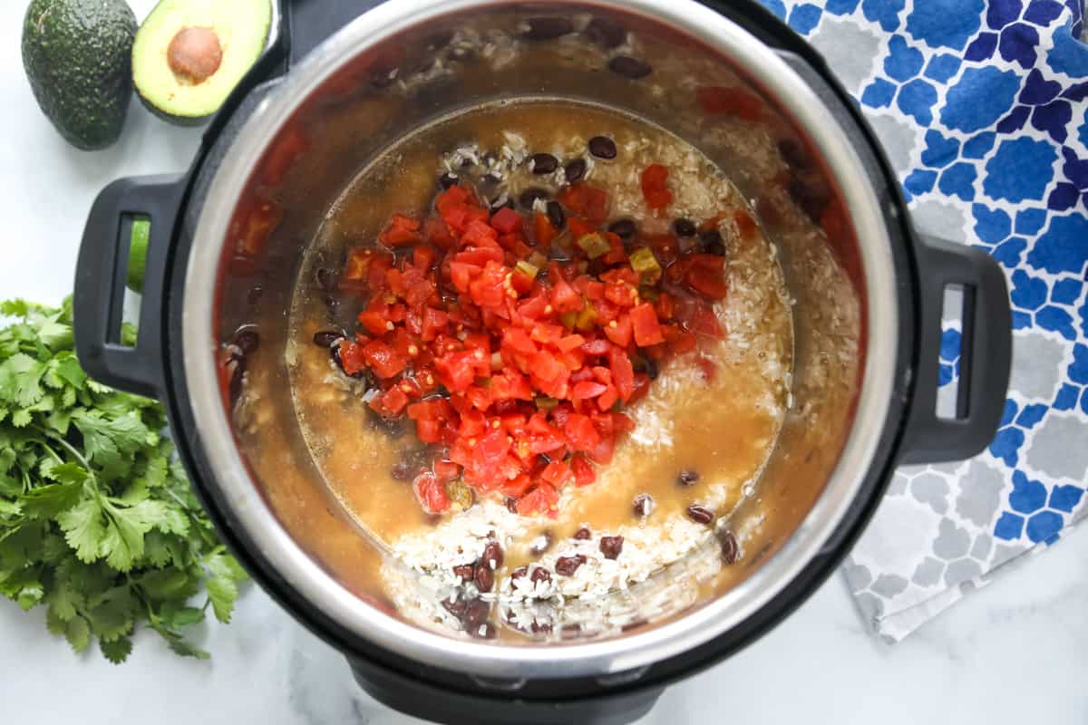 Rice, beans, chicken, and rotel tomatoes in inner pot of instant pot. 