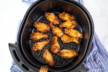 Crispy chicken wings in air fryer basket.