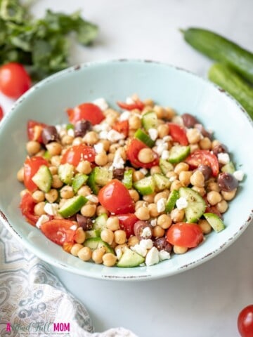 Bowl with Chickpea Salad next to fresh tomatoes and cucumbers.