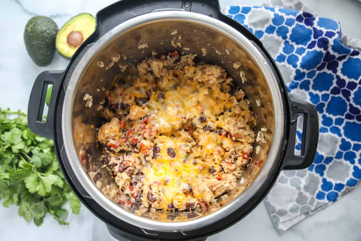 Chicken and rice covered in cheese inside inner pot of instant pot. 