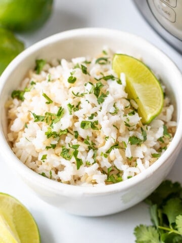 Bowl of cilantrol lime rice next to fresh limes and the Instant Pot.