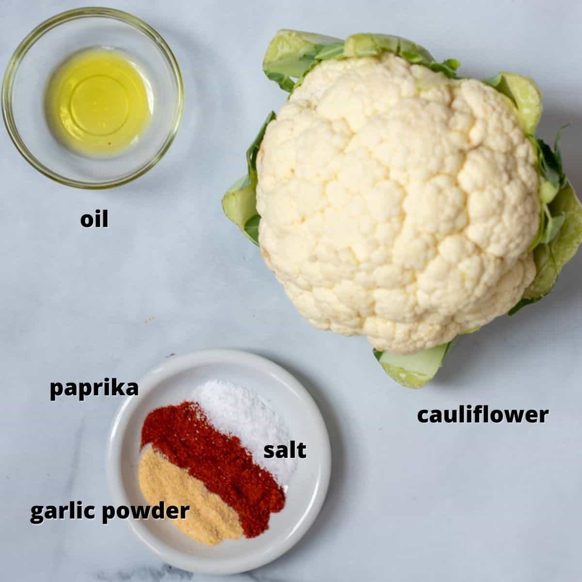 Cauliflower, seasonings, and oil on counter. 