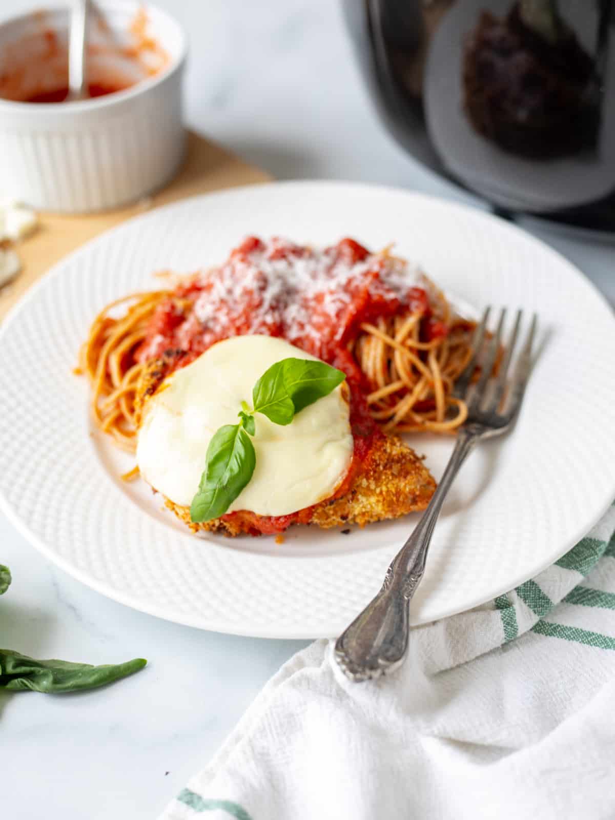 Air Fryer Chicken Parmesan on white plate served with side of spaghetti.