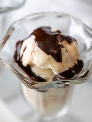 Homemade vanilla ice cream in sundae bowl topped with hot fudge.