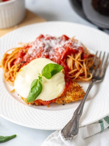 Air Fryer Chicken Parmesan on white plate served with side of spaghetti.