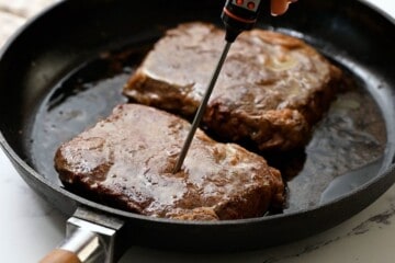 Inserting a thermometer into center of ribeye steak.