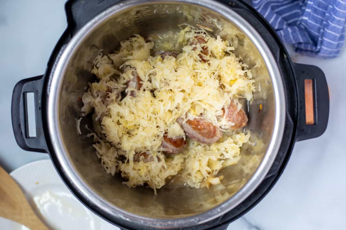 Brats with sauerkraut and onions in inner pot of Instant Pot.