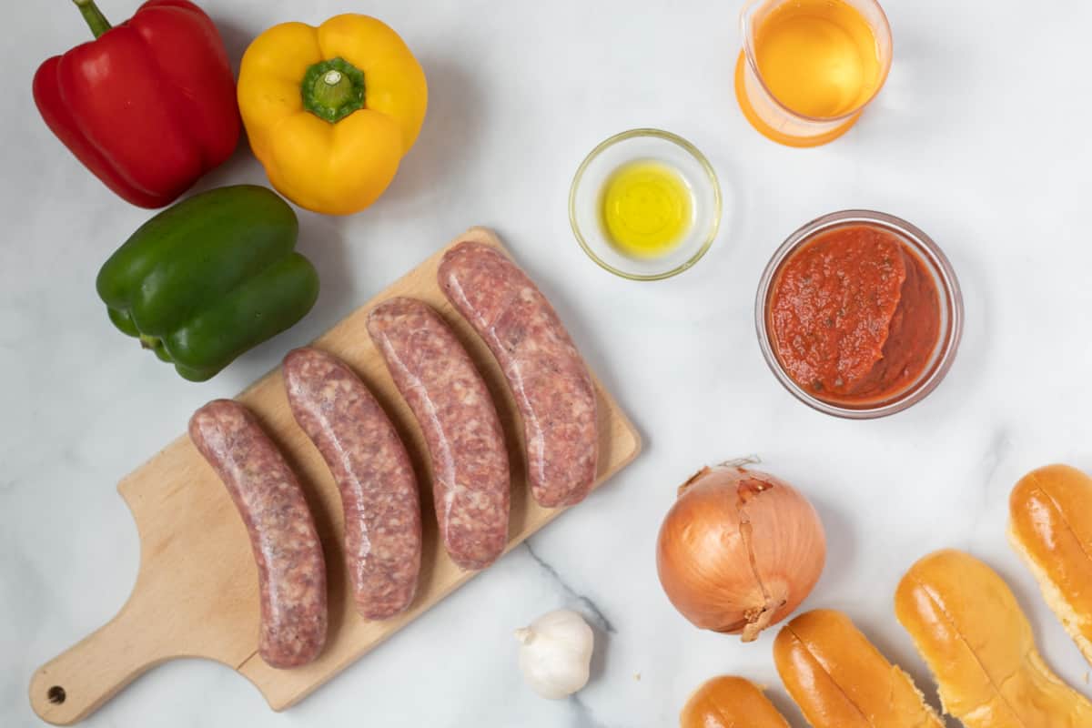 Ingredients for sausage and peppers on white counter. 