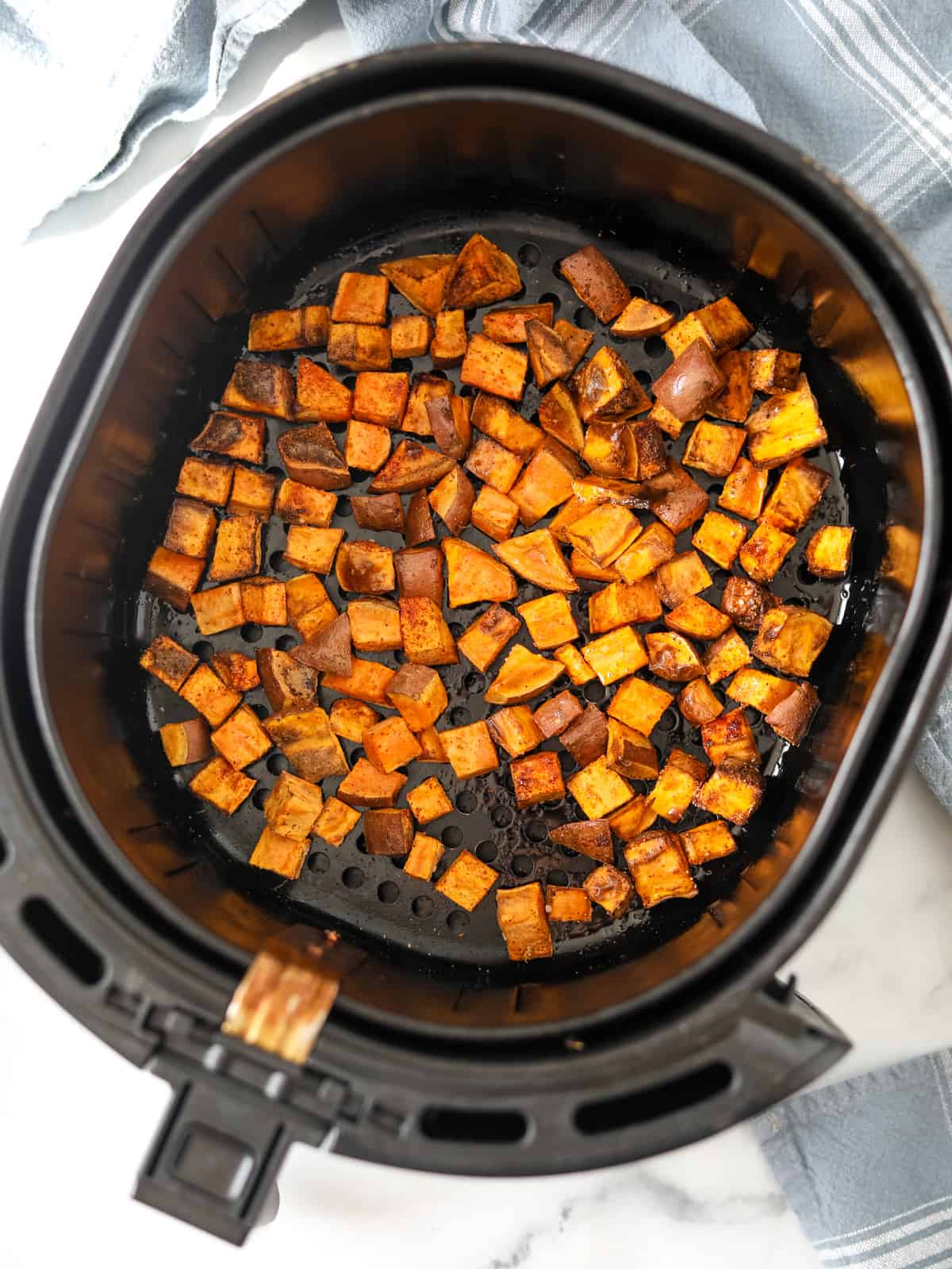 Air Fryer Basket with cubed roasted sweet potatoes. 
