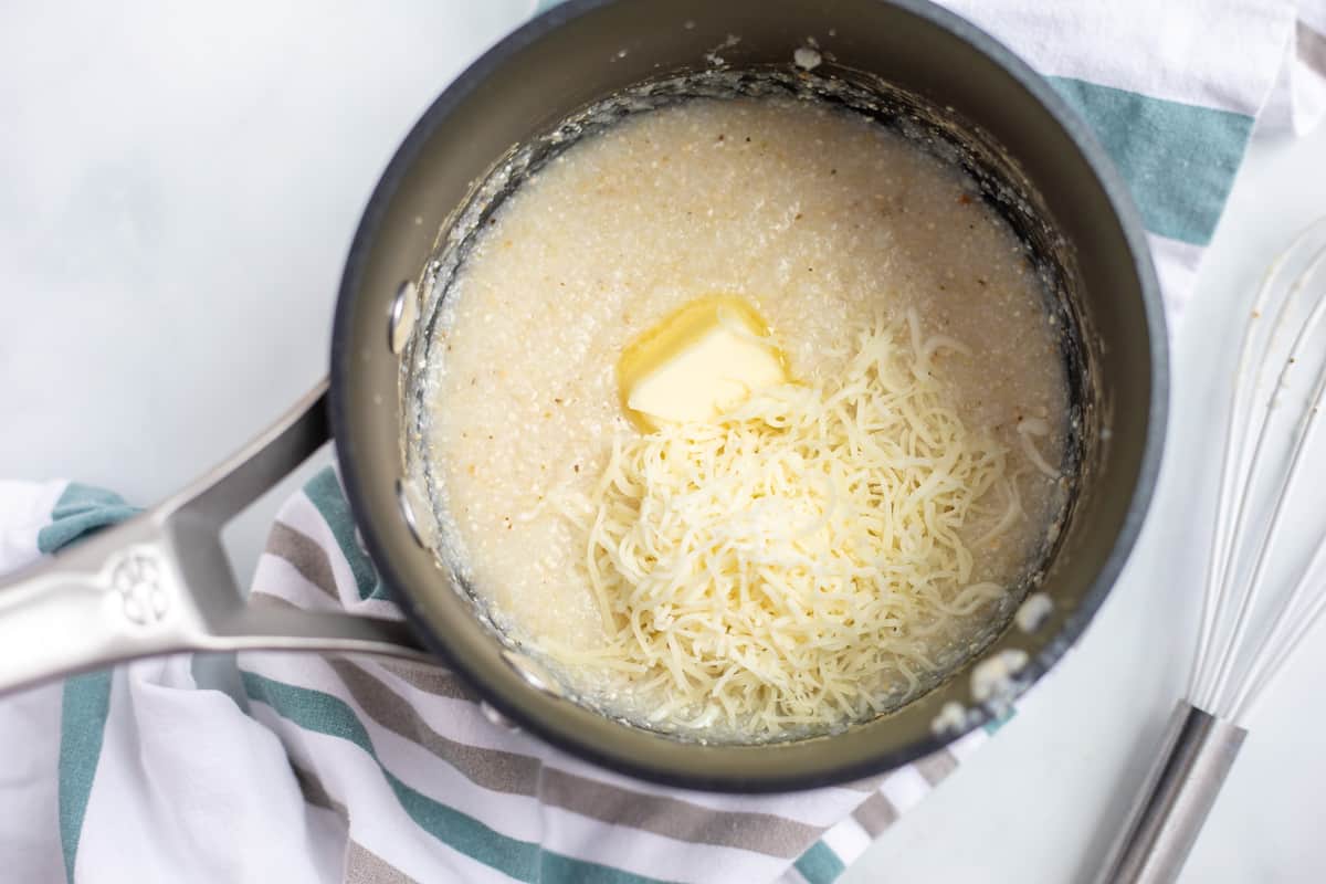 Saucepan with grits, butter, and cheese in the pan. 