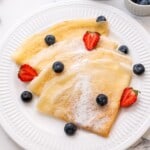 Crepes on white plate with fresh berries.