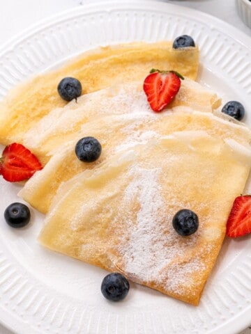 Crepes on white plate with fresh berries.