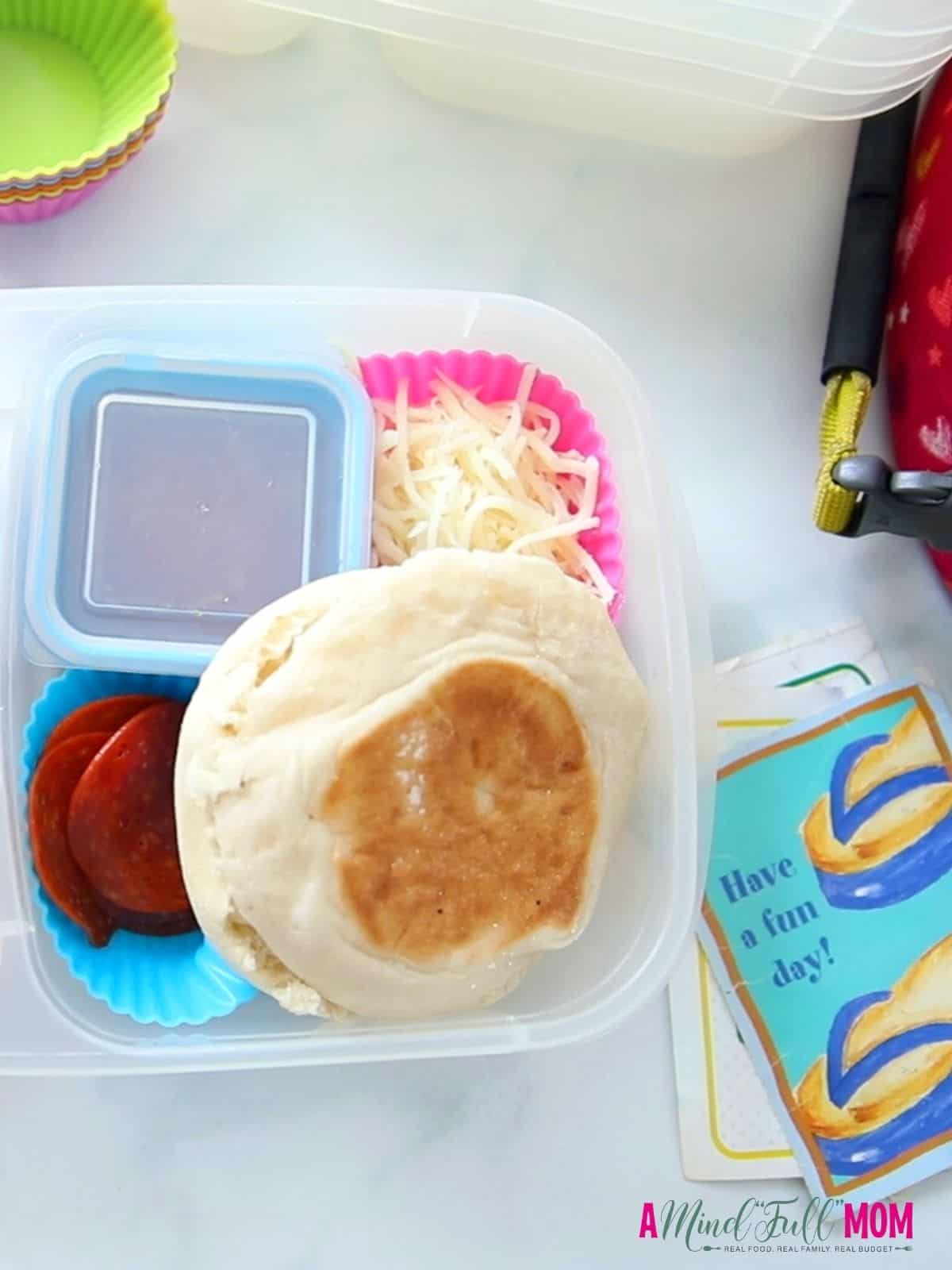 Lunch container with english muffin lunchable and school note. 