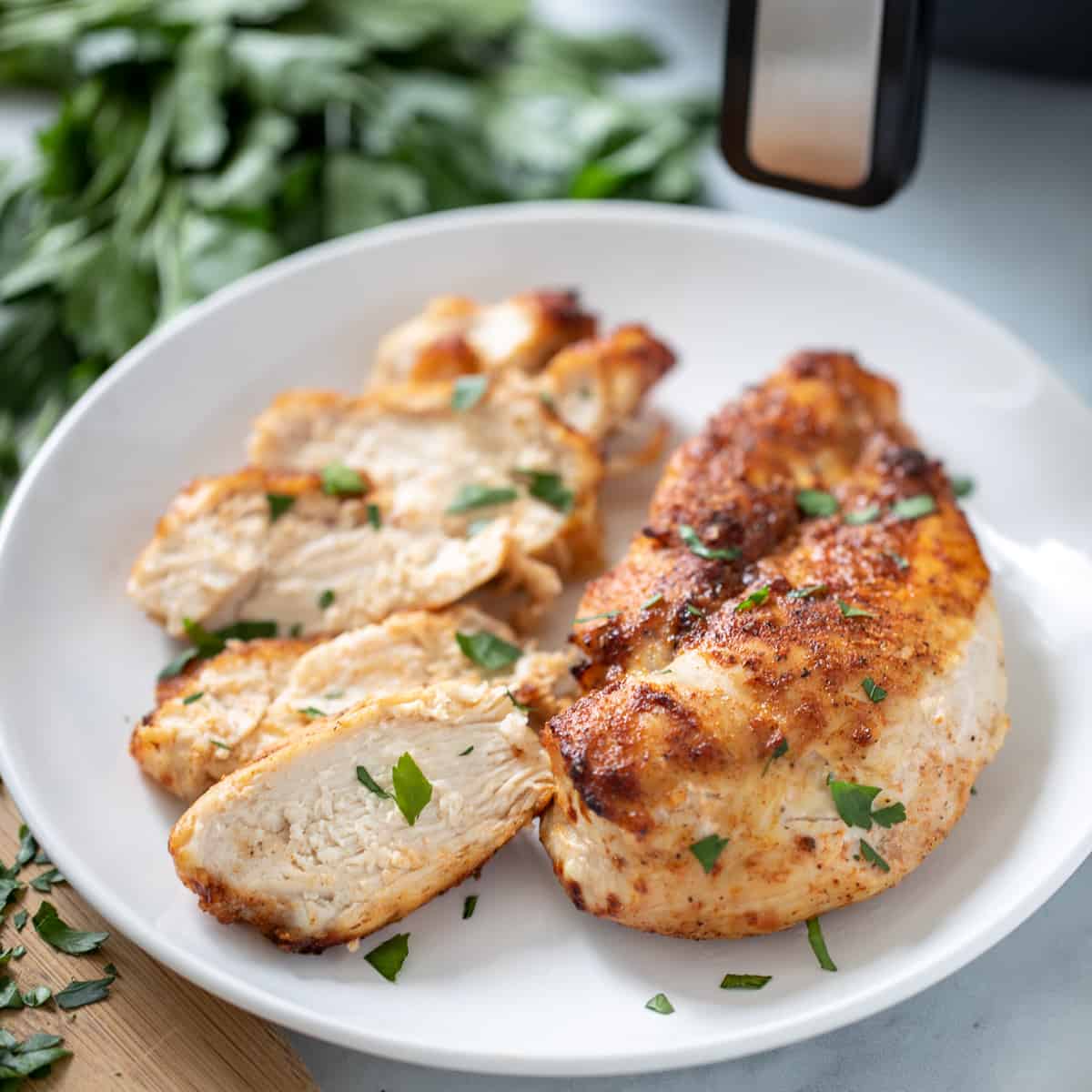 Air Fryer Chicken Breasts on white platter topped with parsley.